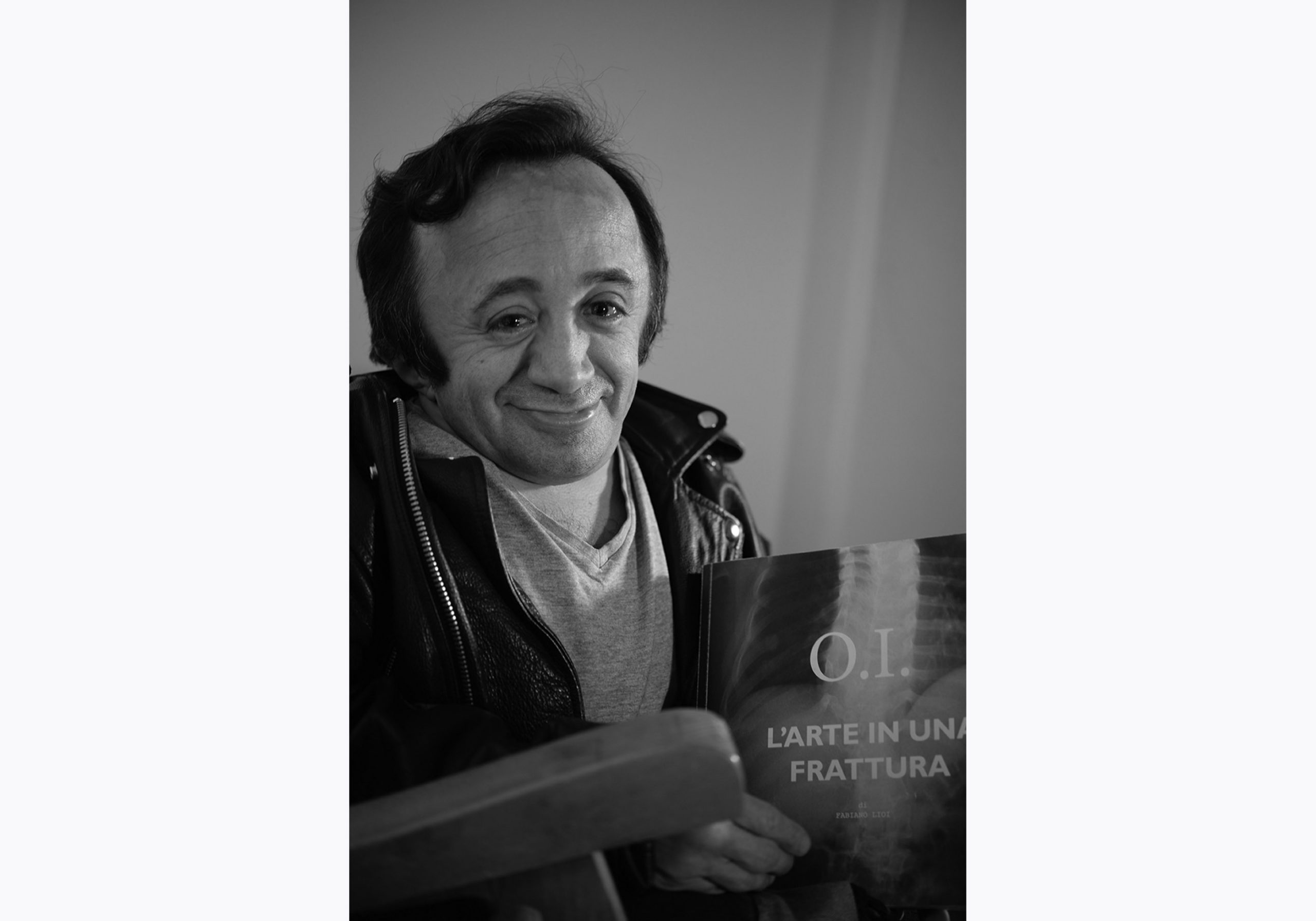 Fabiano Lioi è l'autore di O.I. L'arte in una frattura. Stampiamo insieme il libro con la campagna di crowdfunding. In questa foto tiene in mano la prova stampa del libro e guarda sorridente in macchina.